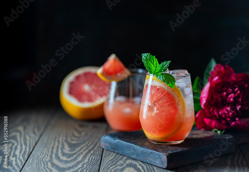 A glass of freshly squeezed grapefruit juice and mint on a dark wooden table. Refreshing summer cocktail.