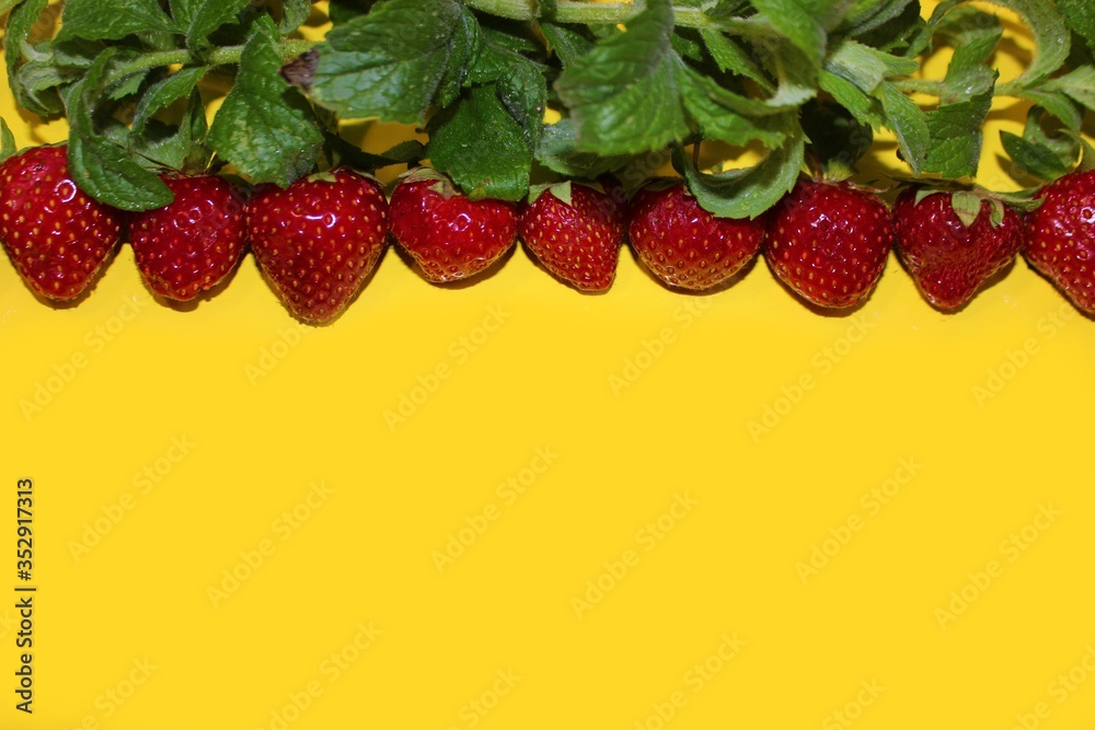 Strawberry berries with mint isolated on a yellow background. Strawberries and mint leaves on a bright yellow background. Background for the design of banners, websites, blogs. Copy space. Red berries