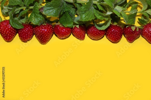 Obraz na płótnie Strawberry berries with mint isolated on a yellow background. Strawberries and mint leaves on a bright yellow background. Background for the design of banners, websites, blogs. Copy space. Red berries w salonie