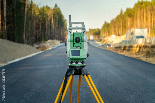 Surveyors equipment (theodolite or total positioning station) on the construction site of the road or building with construction machinery background