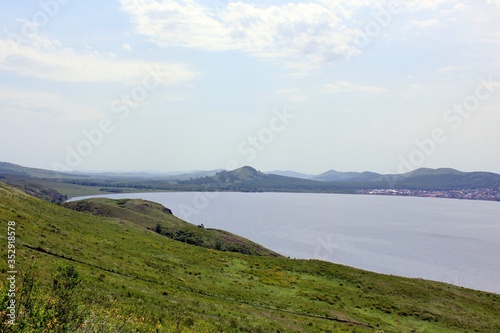 Great panoramic view. A clean mountain lake in the midst of majestic mountains in a haze