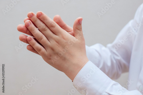 Two hands in a white shirt that have been treated with alcohol-based disinfectants