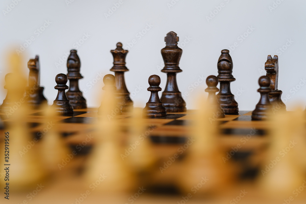 Wooden chess board at starting position with focus on black king Wooden chess board at starting position with focus on black king