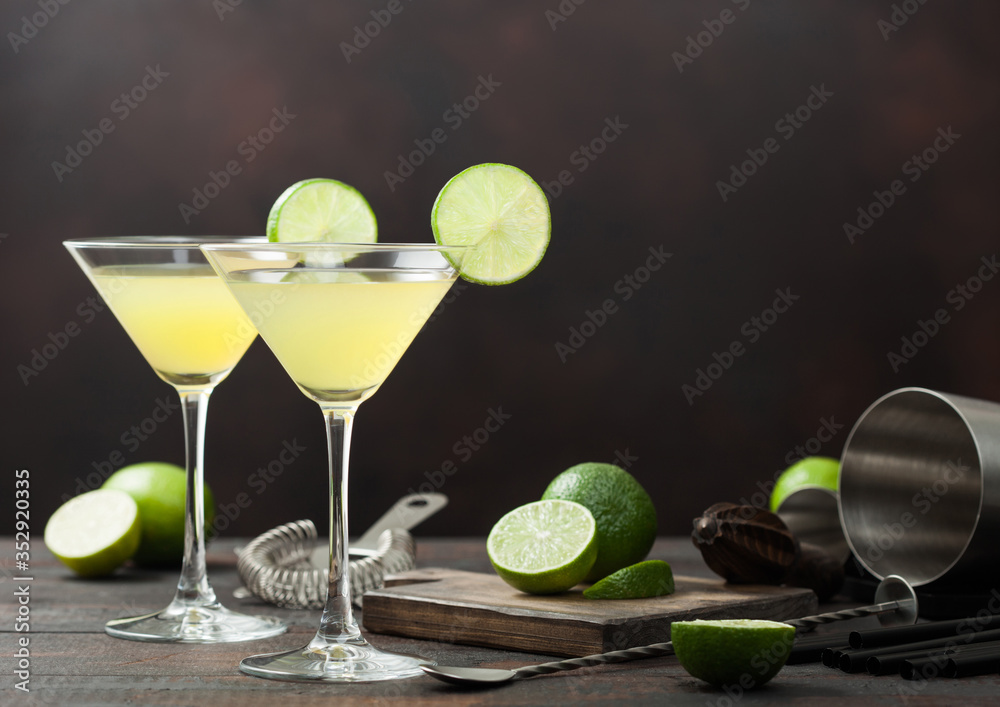 Φωτογραφία Gimlet Kamikaze cocktail in martini glasses with lime slice and ice on wooden board with fresh limes and strainer with shaker