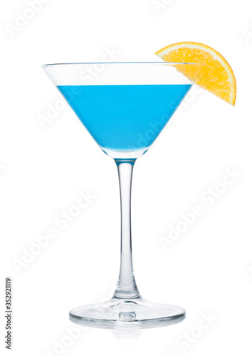 Blue lagoon summer cocktail in martini glass with orange slice on white.