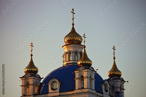 Beautiful Golden domes with crosses close up on Chtistianity Church blue roof on Sunny sunset, symbol of faith