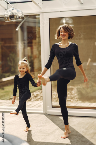 Girl is engaged in gymnastics. Family in a yoga studio. Kid in a black sportwear.