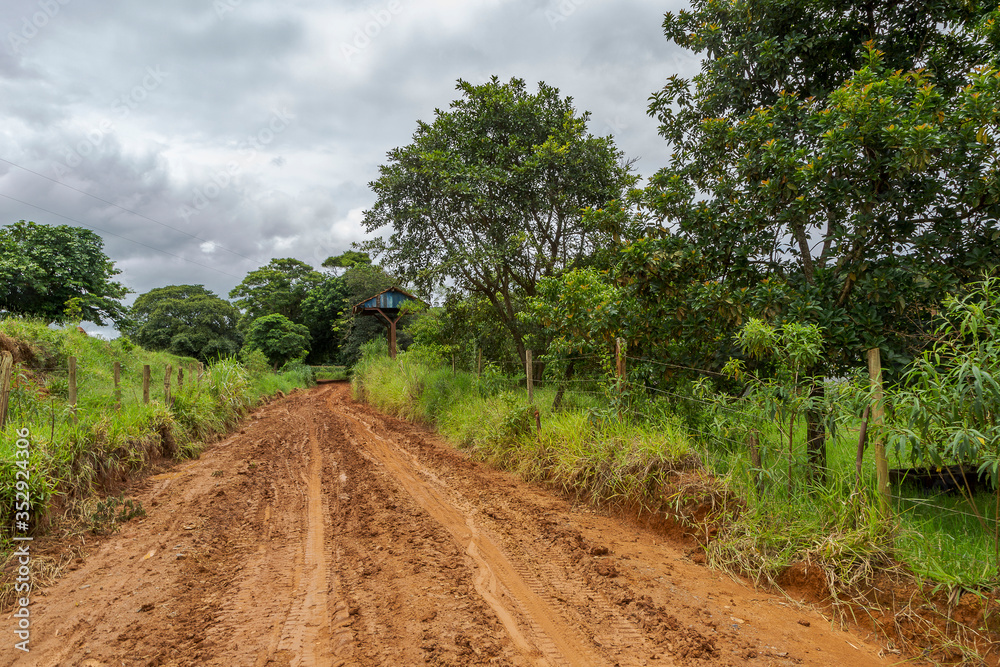 Estrada de terra encharcada por água de chuva e barro, em área rural de Guarani, estado de Minas Gerais, Brasil.