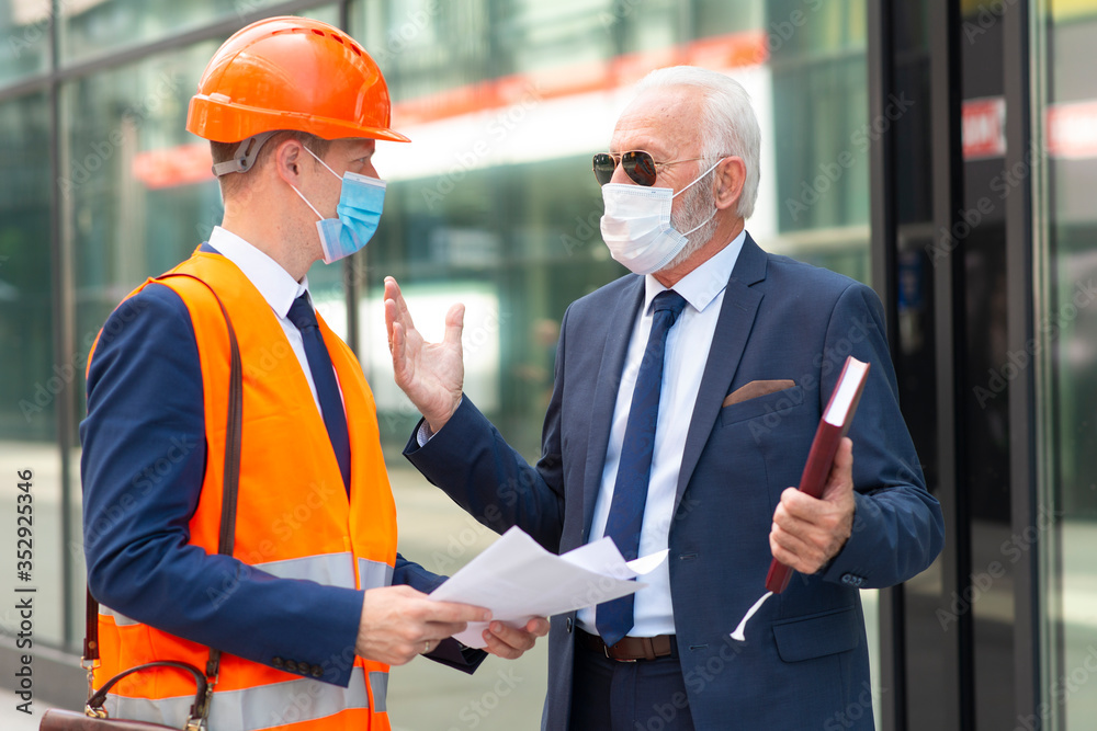 Engineer man with mask discussing something with senior business man with mask Engineer man with mask discussing something with senior business man with mask