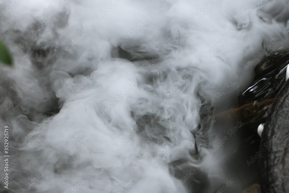 Defocused and blurred image for background. White steam,Hot Springs, Boiling and steaming water in geyser vent, Large stones arranged, Boiling water splash. closeup, vintage style.