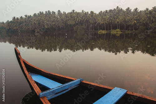 Fototapeta Naklejka Na Ścianę i Meble -  Wooden boat on the backwater canals on a background of tropical forest with palm trees. Copy, empty space for text