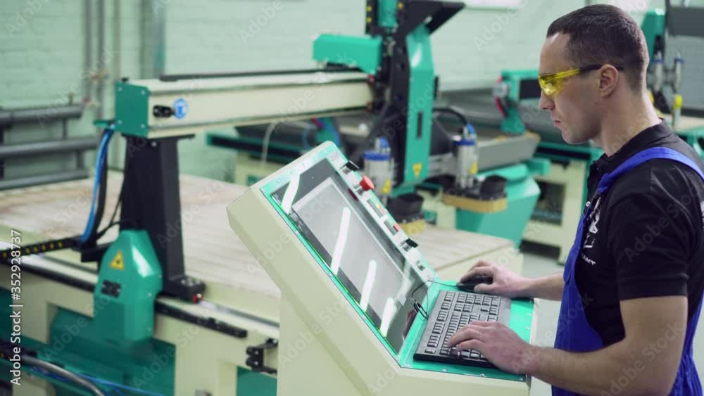 A male operator controls the CNC machine while standing at the control panel. A male operator controls the CNC machine while standing at the control panel.