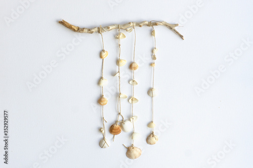 Handmade seashell mobile. Seashells hanging in the middle of a white background. Sea and summer decoration concept.