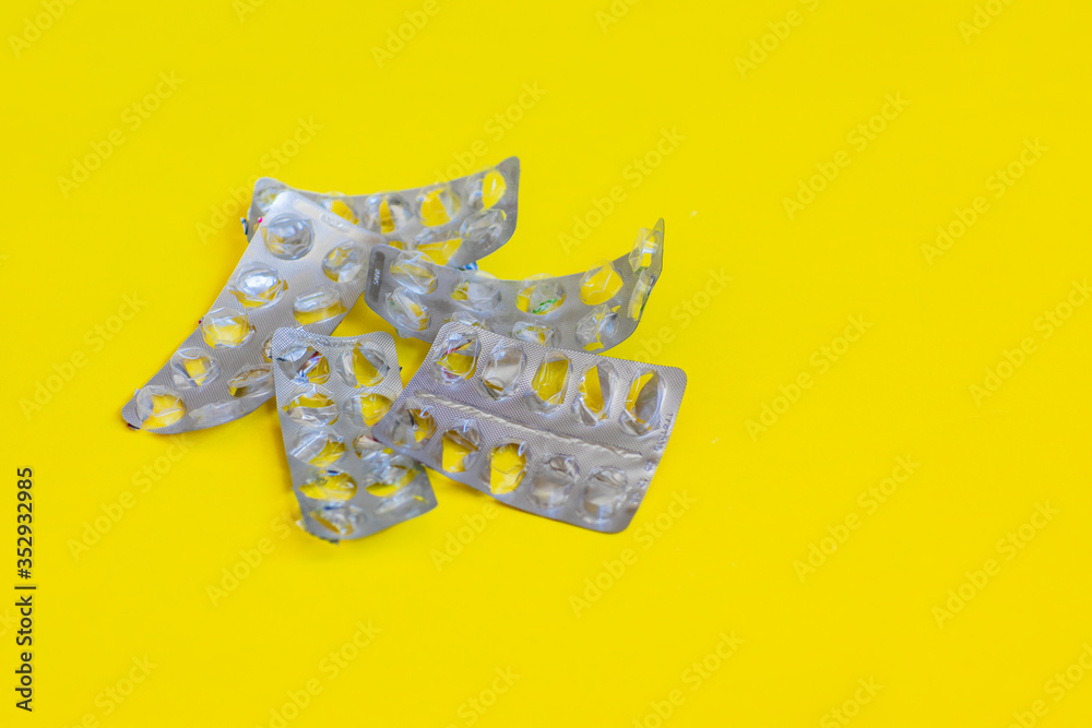 Empty pills packings on a yellow background 