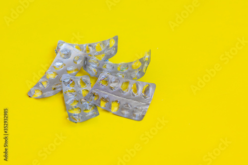 Empty pills packings on a yellow background 