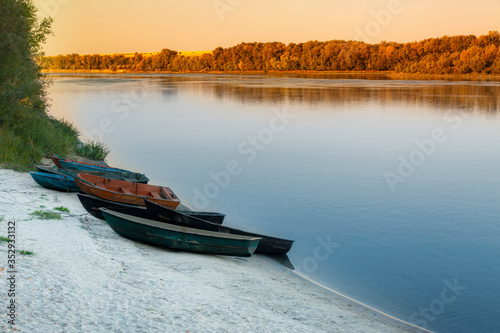 Evening, boats on the sandy shore near the river.