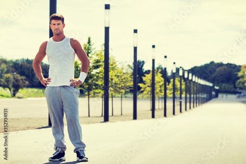 Portrait of young attractive man wearing sports wear standing in park
 photo