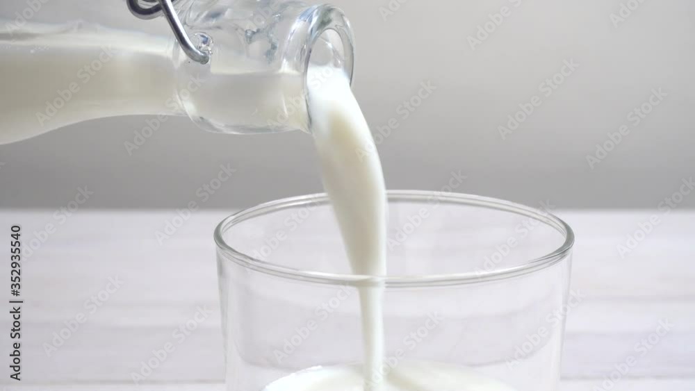Vertiendo leche en un vaso en la mesa