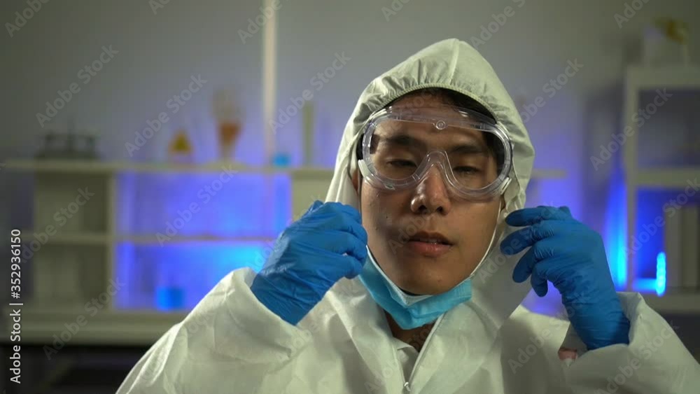 Young Asian handsome man scientist removing face mask, eye protection glass smiling looking at camera in laboratory. Doctor and scientist work in laboratory pandemic of corona virus, COVID19 concept Young Asian handsome man scientist removing face mask, eye protection glass smiling looking at camera in laboratory. Doctor and scientist work in laboratory pandemic of corona virus, COVID19 concept
