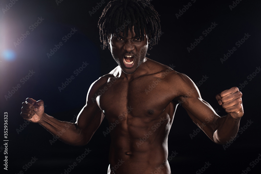 muscular emotional african american man shouting on black with back light