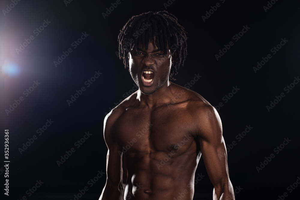 Obraz premium sexy aggressive african american man yelling on black with back light