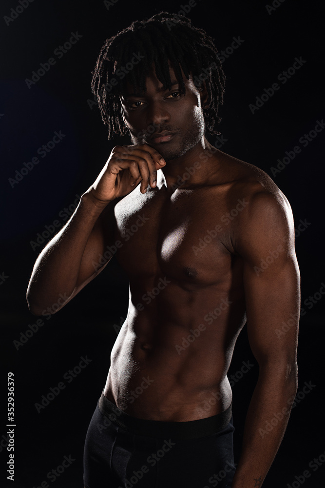 sexy shirtless muscular african american man isolated on black with back light