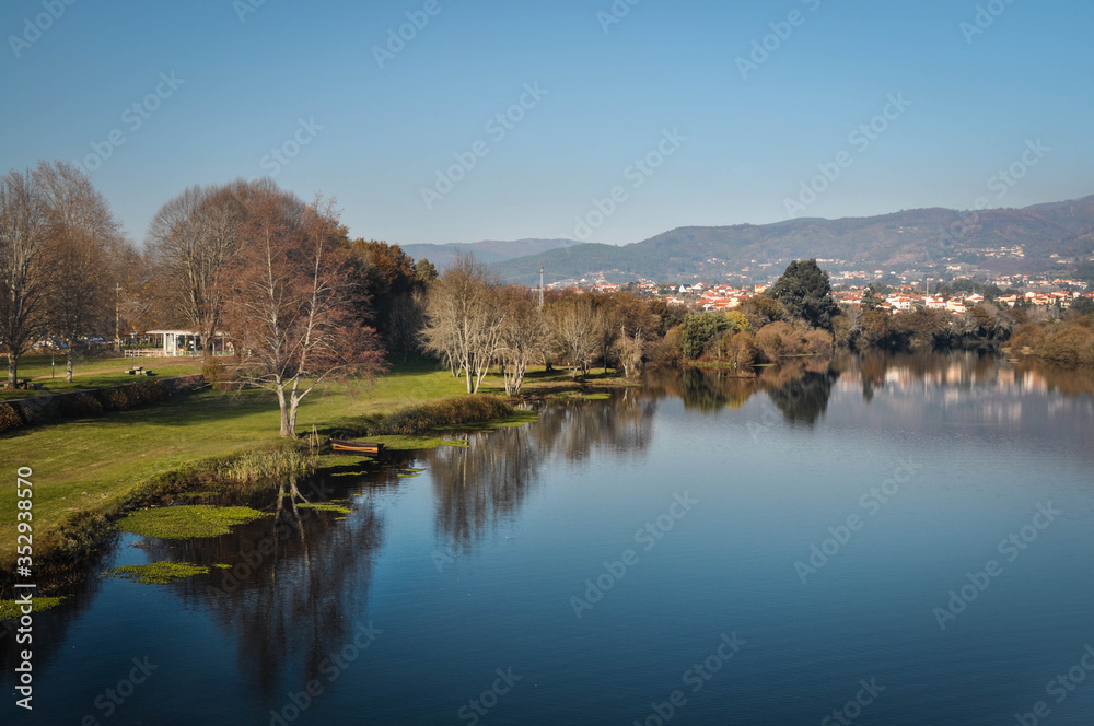 The river through the park and the city is reflected in the water. In the background of mountain and city. Ponte de Lima Portugal.