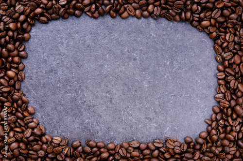 Frame made from roasted coffee beans over grey stone background with space for copy text