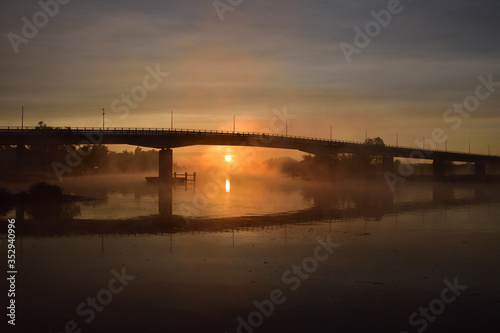 Wschód słońca i most nad rzeką spowite w oparach magicznej mgły. 
