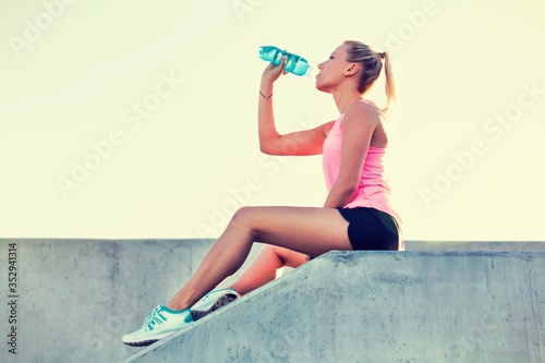 Young attractive woman sitting while drinking energy drink 