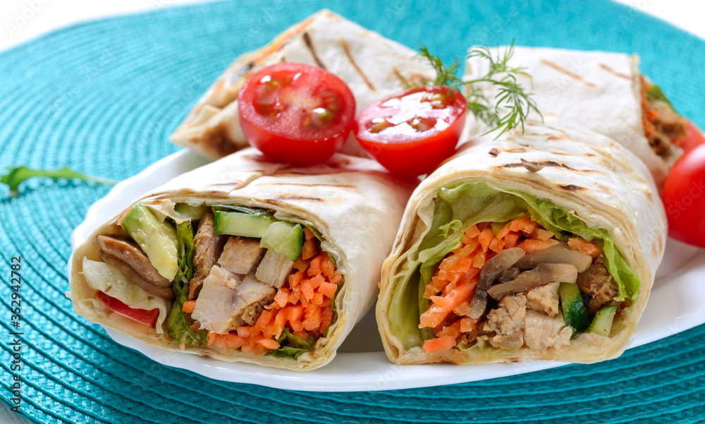 Fresh tortilla wraps with chicken, mushrooms and fresh vegetables. Chicken Mexican burrito. Tasty appetizer. Dishes from pita bread. Healthy food concept Fresh tortilla wraps with chicken, mushrooms and fresh vegetables. Chicken Mexican burrito. Tasty appetizer. Dishes from pita bread. Healthy food concept