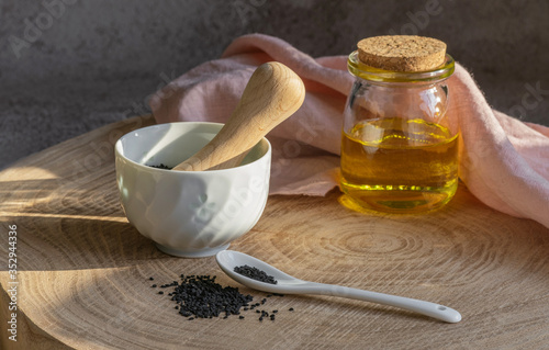 Black cumin seeds and essential oil with bowl and ceramic spoon. Nigella Sativa in glass bottle. Organic herbal medicine for many diseases
