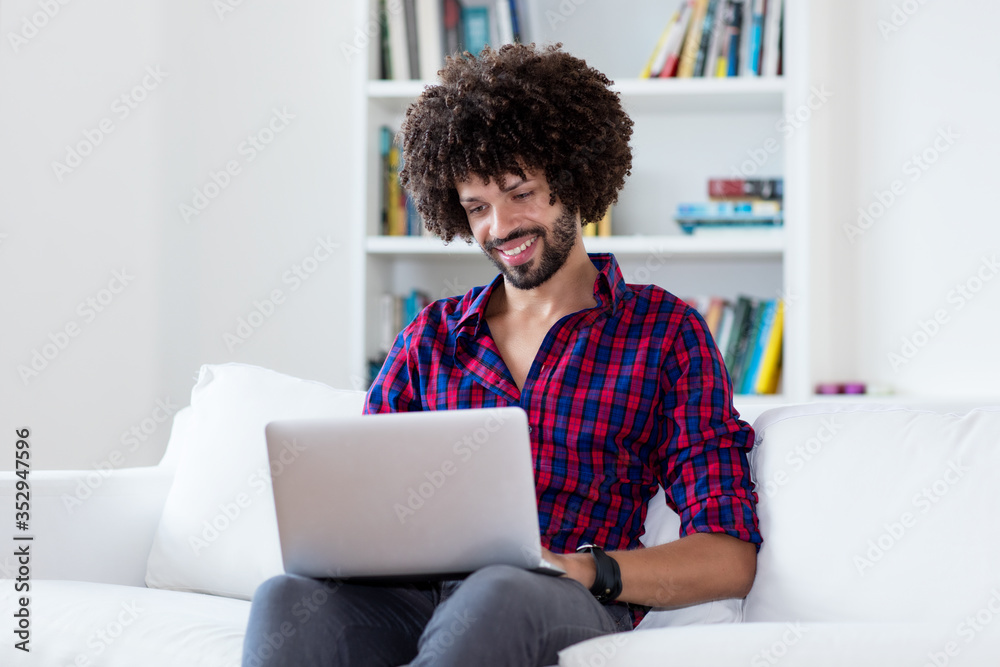 Laughing latin american hipster man in quarantine at computer Laughing latin american hipster man in quarantine at computer