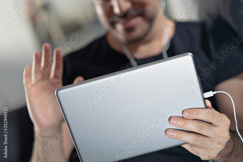 man holding using digital tablet and headphones sitting on a sofa. Online education, working, video call photo