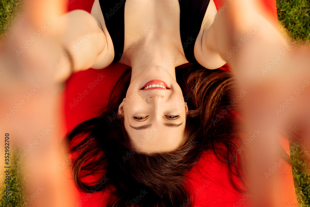 Naklejka premium Pretty young woman smile to the camera lying on a sports mat