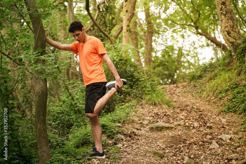 boy with orange shirt during a run in the woods. Flare and light effect, scenic shot. Low point of view. Ideal for concept of fredoom, happiness and adventure.