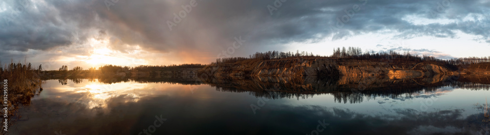 Mirror image in the lake of steep banks at sunset. Vsevolozhsk. Leningrad region.