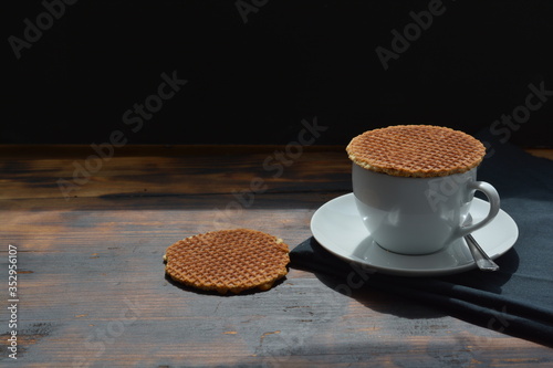 Dutch stroopwafels on top of a cup of coffee on a wooden table