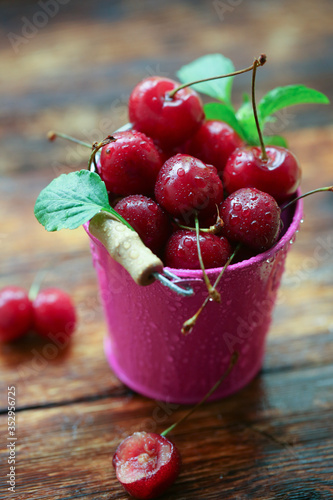 A bucket of cherries on a wooden table. 