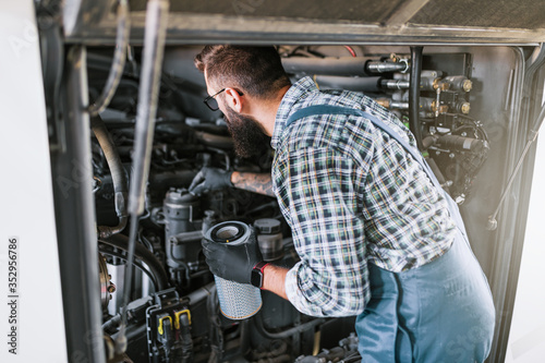 Bus maintenance worker checking oil level and filter condition