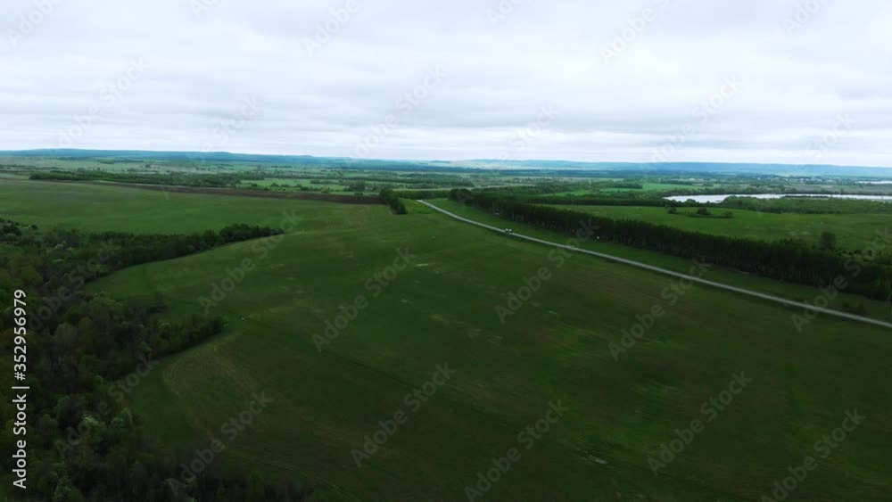 Green field and trees from the highway with moving cars. The view from the top Green field and trees from the highway with moving cars. The view from the top