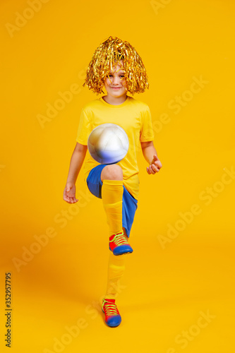teen boy with a soccer ball and pompons for fans on his head