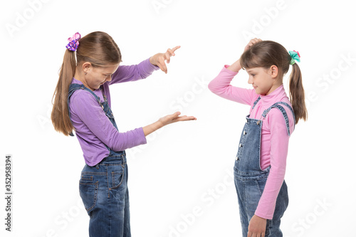 Fotografia A girl shows a virtual object on her hand, another girl looks at her and scratches her head in bewilderment