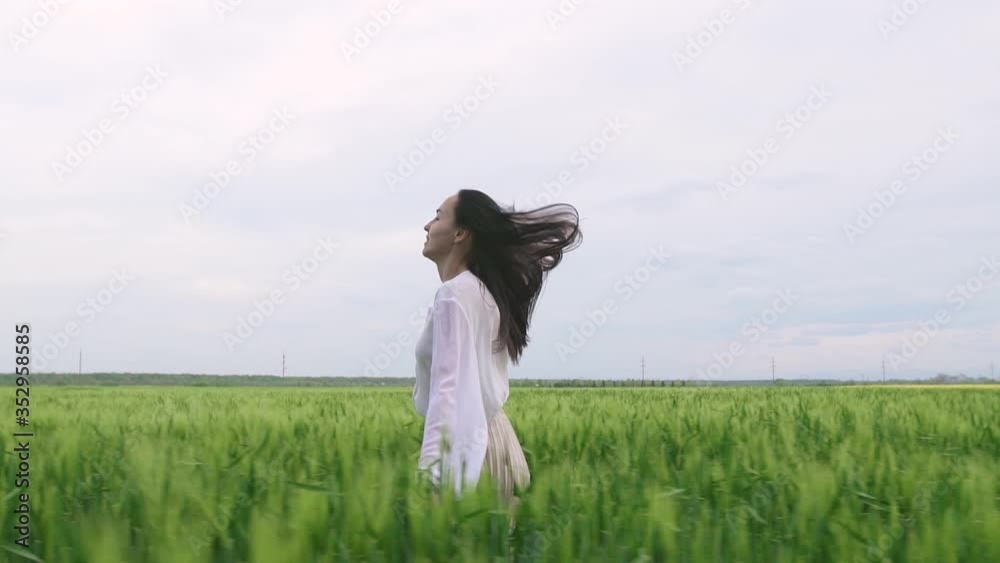 beautiful caucasian girl with black hair in a white shirt and skirt runs across a wheat field at sunset and smiles at the camera beautiful caucasian girl with black hair in a white shirt and skirt runs across a wheat field at sunset and smiles at the camera