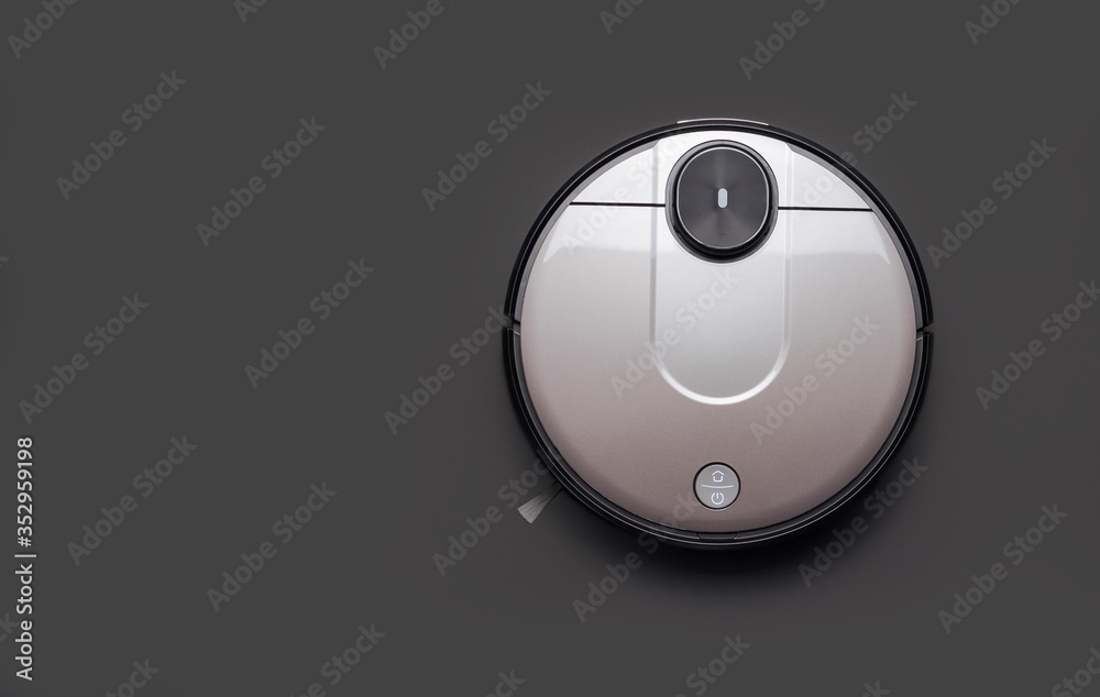 Modern robot vacuum cleaner on black background copy space. New technologies, quick house cleaning, automatic robot assistant. Free time to relax. Future technology, smart appliance for cleaning house