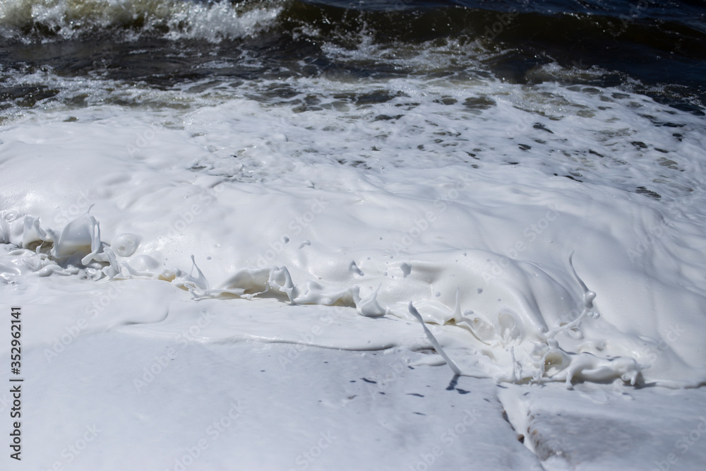 River bank, clear water and white thick foam from the surf.