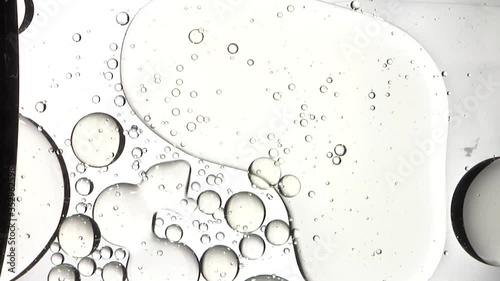 Shot of suspended spheres of air in oil rest on surface of water