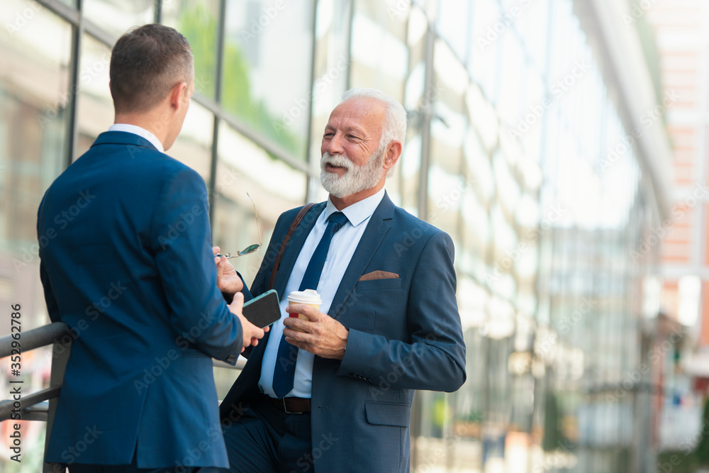 Mature businessman talking with young colleague Mature businessman talking with young colleague