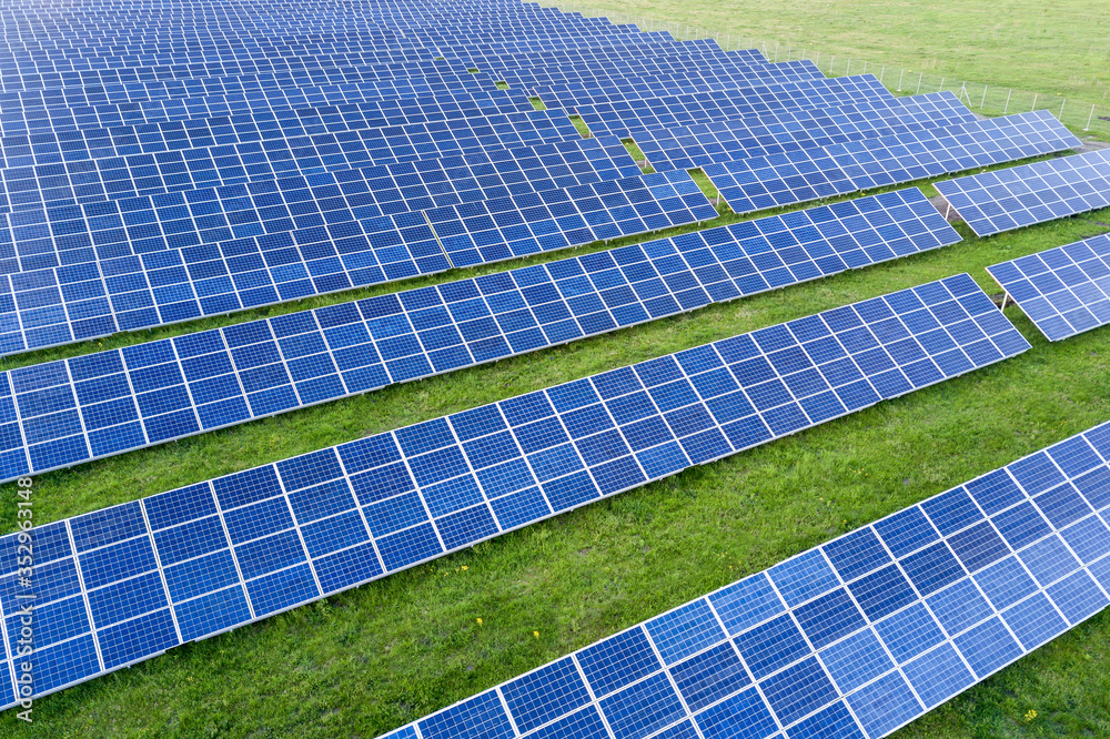 Large field of solar photo voltaic panels system producing renewable clean energy on green grass background. Large field of solar photo voltaic panels system producing renewable clean energy on green grass background.