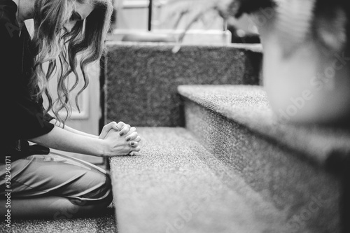 Obraz na plátně Woman at the front of a church kneeling down and praying